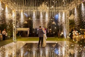  A luxurious wedding scene in Marbella, featuring a couple surrounded by a dazzling display of fireworks and shimmering crystals. The atmosphere is celebratory and opulent, capturing the essence of a high-end, extravagant event.