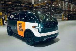 Front and side view of a new Canoo electric vehicle wrapped in black, white and yellow with