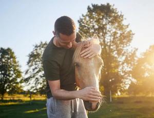 A man nuzzling a horse shows the concept of Equine therapy as a pillar of holistic rehab offerings at Ingrained Recovery