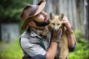Coyote Peterson holding a red fox