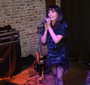 Young singer in blue sequin dress with feather trim.