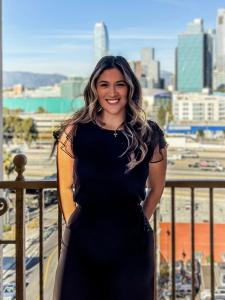 Samantha Huerta, an accomplished Latina in technology and president of #LatinaGeeks Los Angeles, stands with confidence in front of the Los Angeles skyline. She is a Microsoft Digital App and Cloud Solution Architect, a first-generation college graduate,