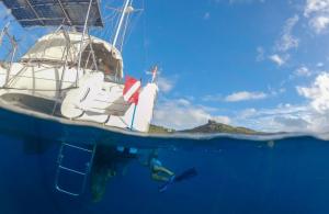 A diver underwater cleaning the hull of a boat using a BLU3 Nomad portable battery-powered dive system.