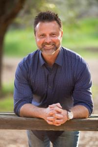 Image of man leaning against a rail, smiling