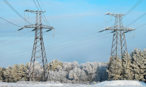 An overhead cable line runs through the snowy mountains. The cable line stretches along a rolling ridge, covered in clean white snow.