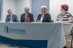 Found leaders sit at a table with a table cloth that reads Grand Forks Region Economic Development, during a press conference.
