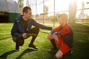 A soccer coach provides training and motivational support to a young soccer player.