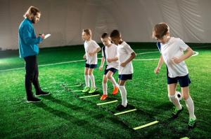 A soccer coach evaluates the young players’ skills during the group training session