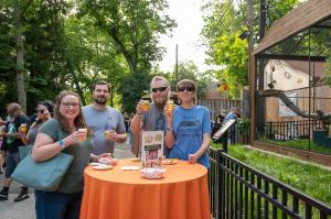 A small gathering of adults gather around a table to enjoy beverages while enjoing the animals at the Brandywine Zoo.