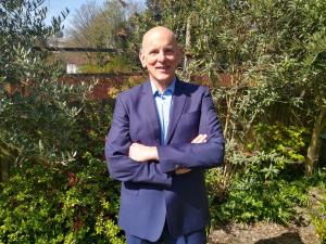 Laurens Holve, osteopath from London UK, standing in a garden wearing a blue suit
