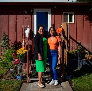 Alma Guzman, Savings Collaborative client turned Community Ambassador, poses in front of the house she was able to purchase as a result of participating in Savings Collaborative. Alma's daughter (right) also started saving through Savings Collaborative.