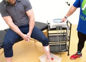 Patient receiving Neubie treatment for neuropathy, with electrodes in the water