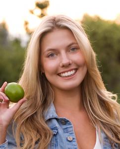 Author and Lyme warrior Olivia Goodreau in a blue demin jacket holding a lime.