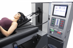 Young female patient laying on the DRX9000 Spinal Decompression Machine Bed and being treated by the DRX9000C Cervical Spinal Decompression Machine.
