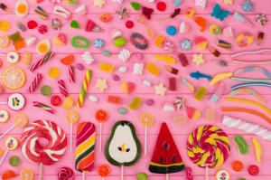 A vibrant array of assorted candies artfully arranged on a charming pink wooden backdrop.