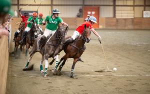 college arena polo players ride after the ball during play
