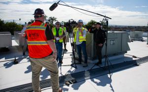Man standing in front of a small camera crew on a commercial building rooftop