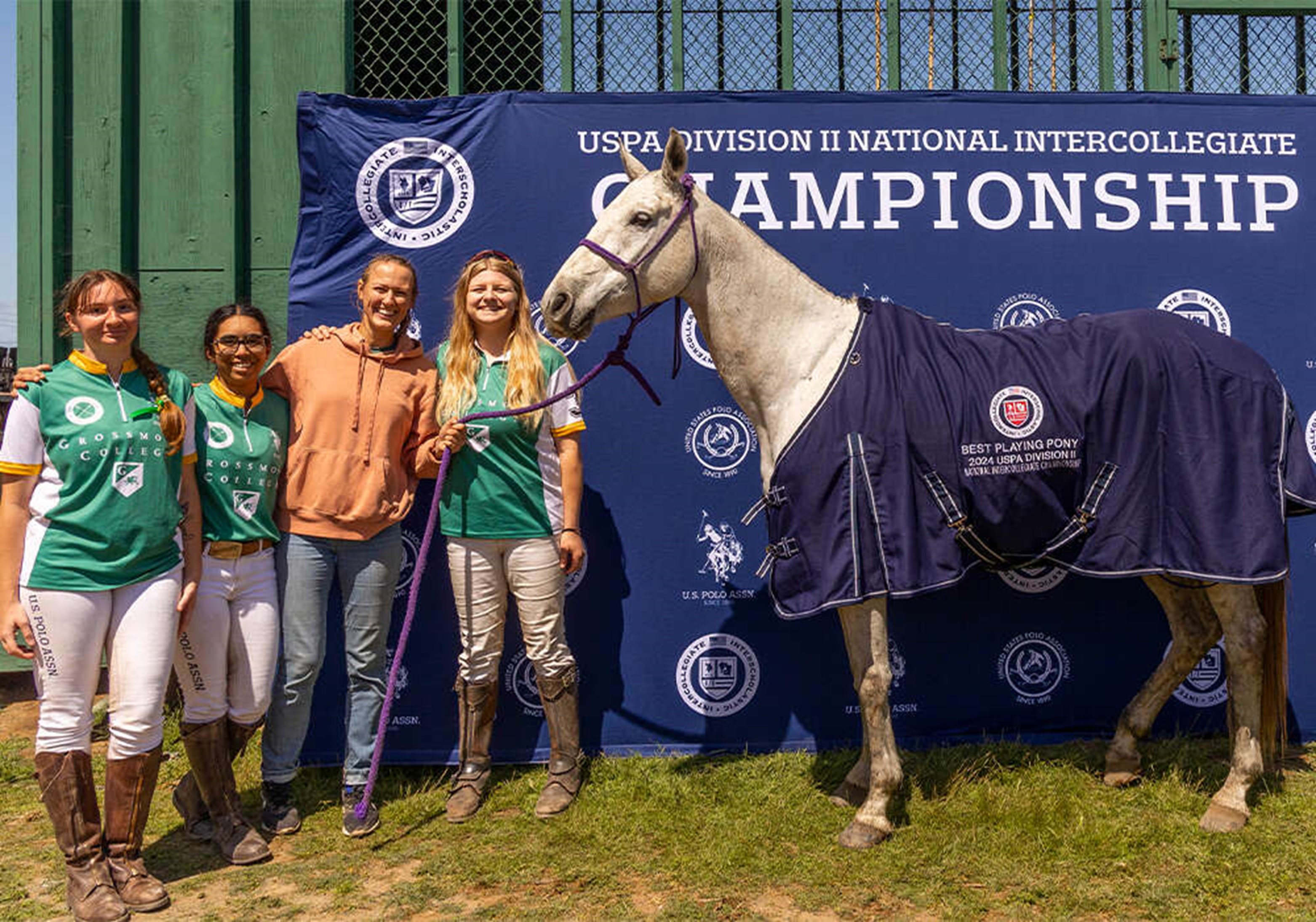 polo players stand beside grey horse