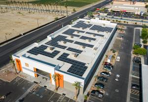 A white building with orange trim in the front and solar panels on the roof.