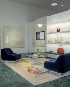 Interior of Reformation Beverly Hills retail store, with modern blue velvet chairs in foreground, atop a rug with a tiger print. Handbags on shelves in background.