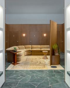Interior of Reformation Beverly Hills retail store, dressing room with beige velvet sectional, wooden paneling, plants, and marble flooring.