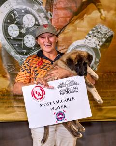 Women arena polo player holds her MVP award and puppy