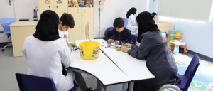 Children gathered around with therapist at Prince Faisal Bin Salman Autism Center