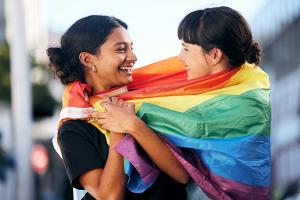 Two Indian women holding a rainbow flag, representing the strength and solidarity of the LGBTQ community in India
