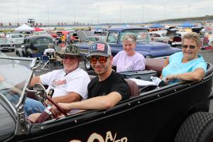 people cruising the speedway in a vintage roadster