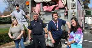 Students and a CFD firefighter pose by a pink firetruck.