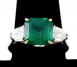 Richard Krementz. emerald and diamond ring in platinum and 18k yellow gold, with a square shaped green emerald weighing 4.44 total carats, set in between accent diamonds ($30,250).