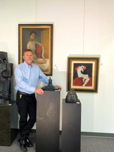 A businessman standing in front of paintings and sculptures