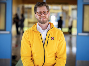 Luke Hostetter, Executive Director of City Year San Jose/Silicon Valley. Luke is standing in a yellow city year jacket, smiling to the camera.
