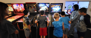 A group of children playing at the Spinners Pinball Arcade.