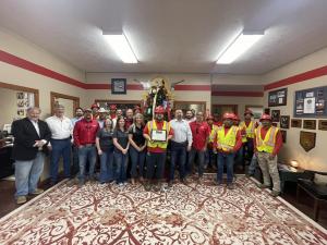 30 members of the Schulte Roofing staff standing in their office for a group photo with the person in the center holding the Safety Excellence Award.
