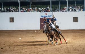An arena polo player carries the ball while horseback in front of a large crowd during the International Arena Polo Championship in India