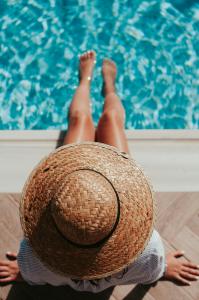 birds-eye view on a woman sitting on a pool wearing a big sun hat during summer