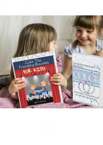 two little girls about age six are smiling and showing each other their new Taylor Swift Coloring Books. One is called Color the Friendship Bracelets, and the other is called Color the Friendship Bracelets for Kids.