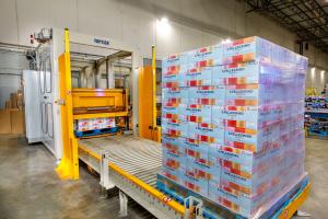 An automated palletizer takes pallets of shrink-wrapped carton packs and seals them for shipment