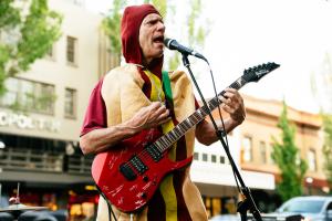 Man in hot dog suit playing guitar and singing at Make Music Salem