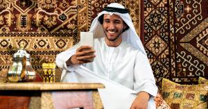 A young Arab man in Dubai using a dating app on his phone, highlighting the importance of secure digital spaces like u2nite for LGBTQ+ individuals.