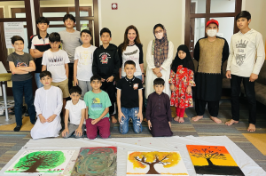 Patti Katter, CEO of The Black Feather Foundation, surrounded by Afghan refugee children showcasing their beautiful artwork created at The Black Feather Foundation's art workshop.