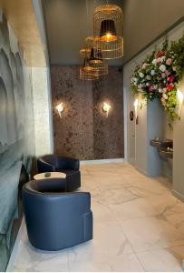 Waiting area with handmade wallpaper, bark wood panelling, marble floor, birdcage lights, floral decor