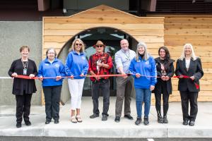 CTCLUSI Tribal Council members stand in front of the Three Rivers Health Center Entrance, designed to resemble a traditional plank house. They prepare to cut the ribbon at Three Rivers Health Center Grand Opening on Saturday, June 1, 2024. From left to ri