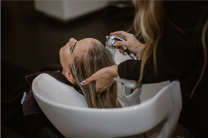 Sideshot of a hair stylist washing a clients hair at the backwash area