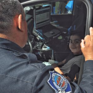 A police officer speaking to a child in a car.
