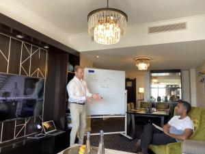 Joe standing in front of a whiteboard, educating a client on the importance of cryptocurrency and its future impact on finance.