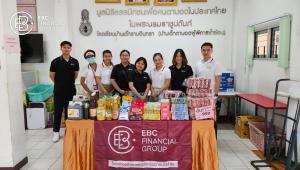 Group photo of EBC Financial Group employees standing in front of the Ramindra Home for Blind Children, surrounded by donated aid items including living and learning supplies.