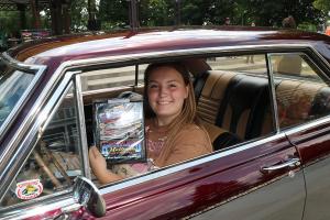 A young lady getting an award for her classic car. 