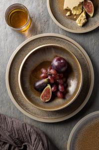 Discover the Enigma dinnerware collection by Utopia, featuring a reactive glaze interior with a semi-matte exterior. The pieces are decorated with caramel tones and accented with raw stoneware, showcasing unique bowl profiles ideal for food presentation.